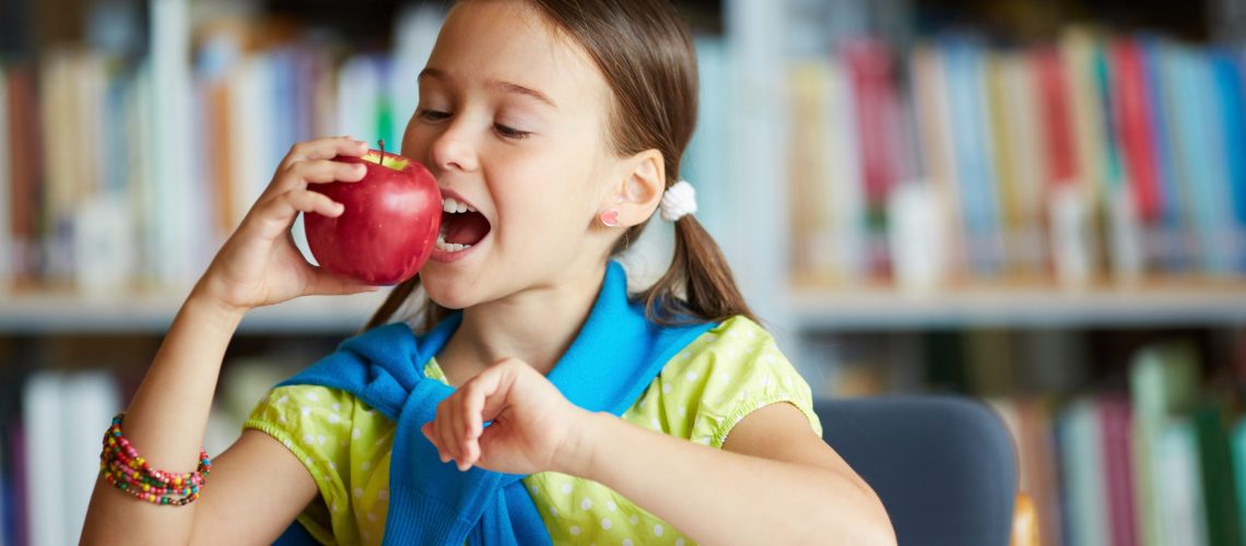 Portrait of healthy schoolgirl eating big red apple